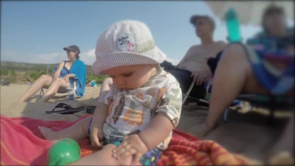 Bebé sentado en la playa con la familia — Vídeos de Stock