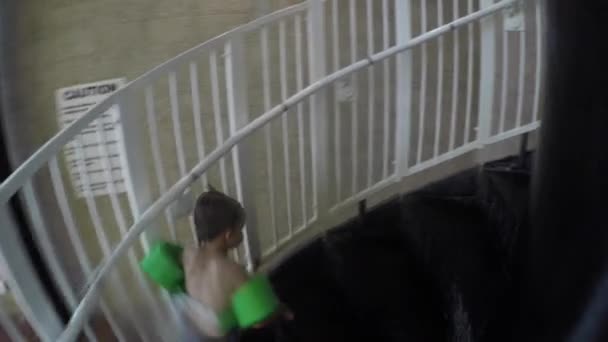 Мальчик поднимается по лестнице на водную горку в бассейне — стоковое видео