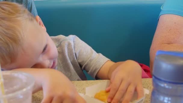 Boy eating chicken nuggets with family — Stock Video