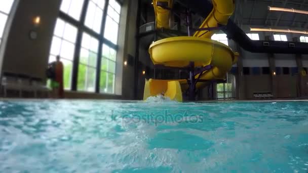 Rapaz desce um escorrega de água na piscina — Vídeo de Stock