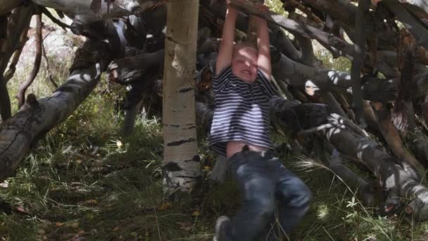 Jongen spelen in een hut gebouwd van stokken — Stockvideo