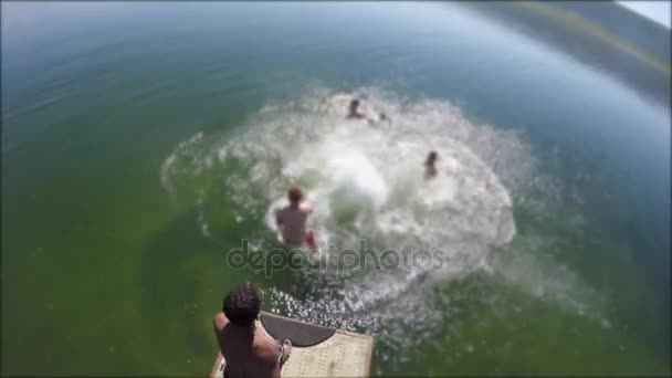 Rapazes saltando no lago da montanha a partir da doca — Vídeo de Stock