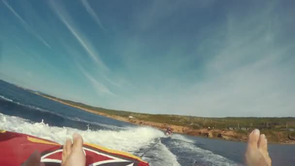 Couple tubing behind a boat in calm ocean — Stock Video