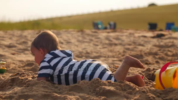 Garçon jouer avec sable et seaux à la plage — Video
