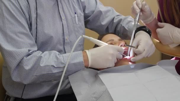 Dentist works on a woman teeth in a chair — Stock Video