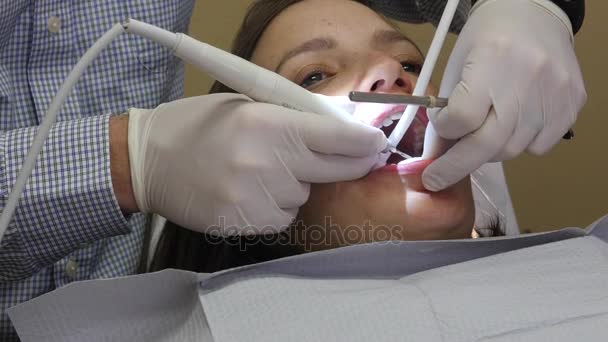 Dentista trabaja en una mujer dientes en su silla — Vídeo de stock