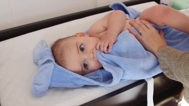 Мальчик за ванной на столике для переодевания в полотенце — стоковое видео