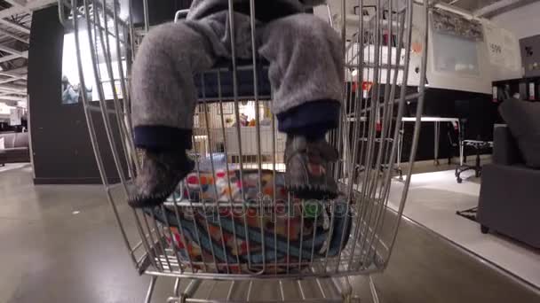 Мальчик сидит в тележке в IKEA — стоковое видео