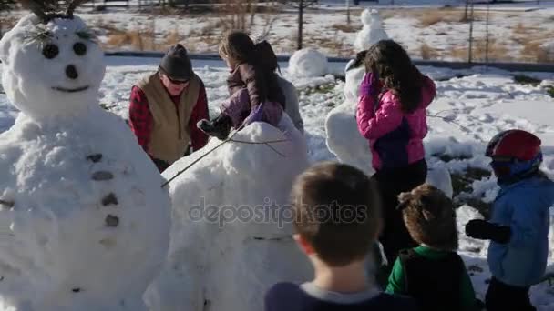 Семья делает снеговиков и горку из снега — стоковое видео