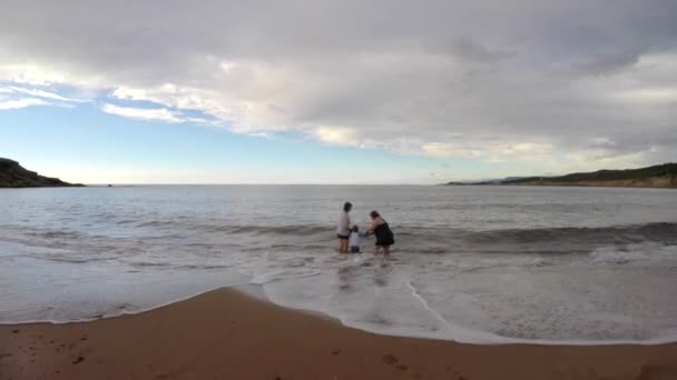 Οικογένεια παίζοντας στα κύματα του ωκεανού στην παραλία — Αρχείο Βίντεο
