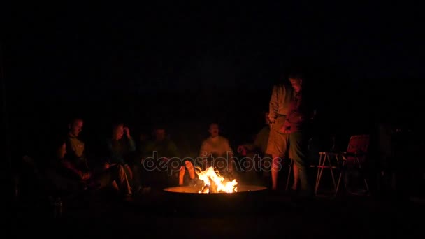 En familj sitter runt en lägereld på natten — Stockvideo