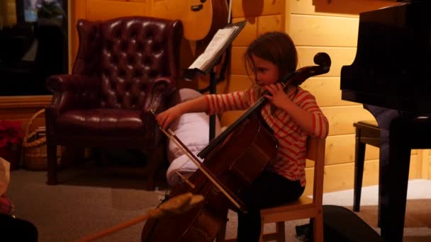 Dívka hraje mistrovské violoncello během vánoční večírek — Stock video