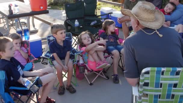 Niños sentados en sillas de campamento mientras acampan — Vídeo de stock