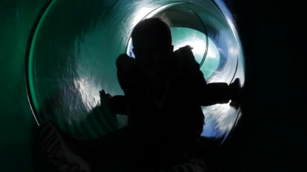 Un petit garçon descend un toboggan au parc — Video