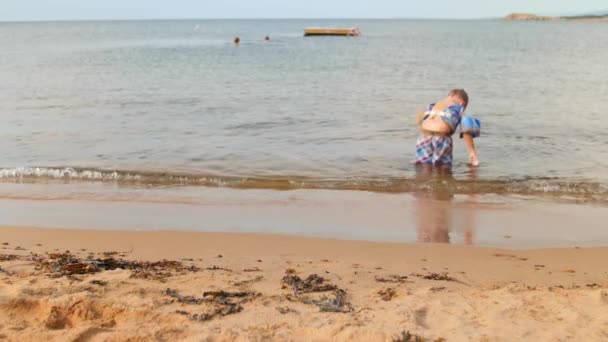 Niño en el océano en la hermosa playa en la arena — Vídeo de stock
