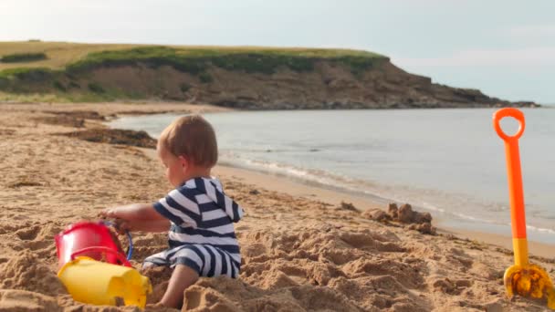 Peuter jongen speelt op het zandstrand — Stockvideo