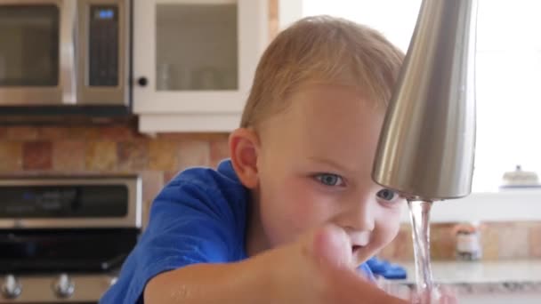 Garçon jouant dans l'évier de cuisine avec l'eau — Video