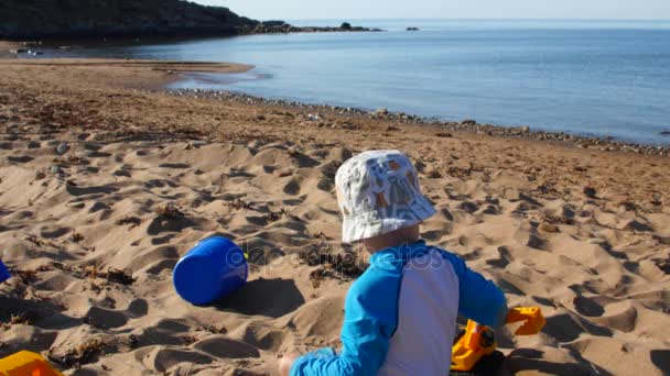 Niño juega con juguetes en la arena en la playa — Vídeos de Stock