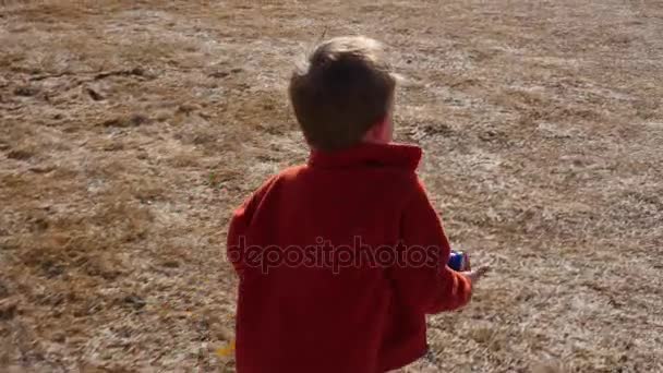 Menino correndo através da grama fora da casa — Vídeo de Stock