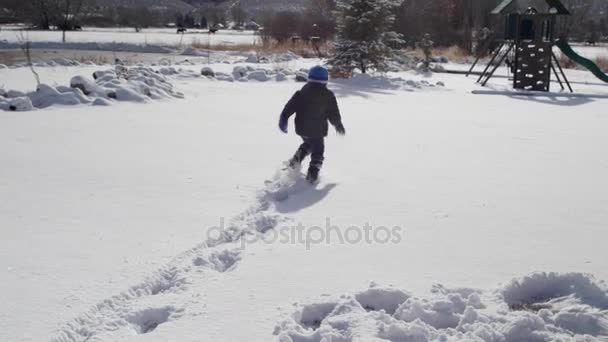 Chico corriendo a través de la nieve fresca — Vídeo de stock