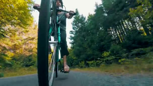Женщина катается на велосипеде в лесу по велосипедной дорожке — стоковое видео