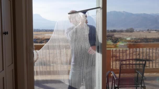 Hombre limpiando las grandes ventanas de la casa — Vídeo de stock