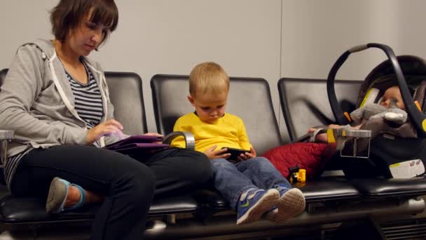 Мама і хлопчик дивитися їх iphone і планшетних — стокове відео