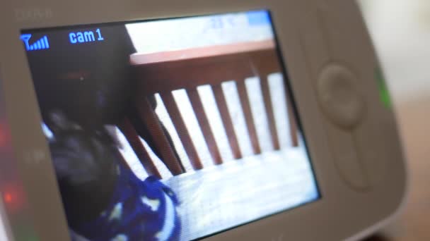 Mor lyfter barn utanför babysäng sett genom monitor — Stockvideo
