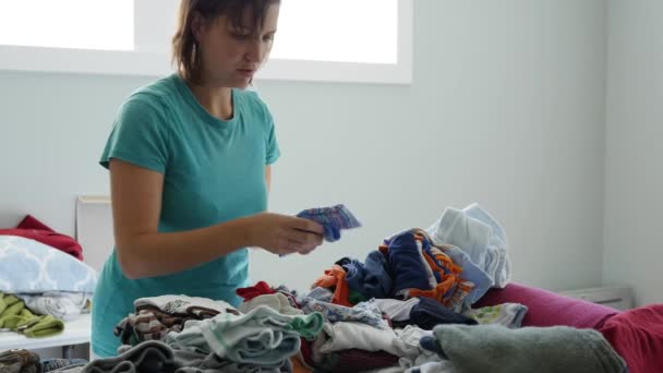 Matka sortuje poprzez ubrania dla dzieci — Wideo stockowe
