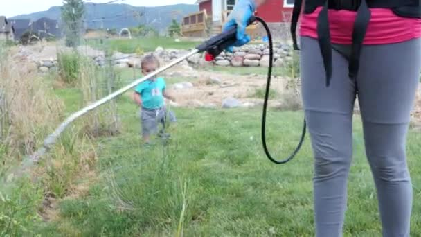 Madre con un niño rocía malezas con herbicida — Vídeo de stock