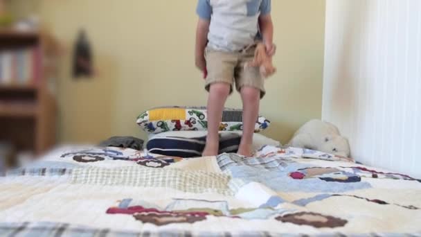 Peuter met een cape springt op zijn bed — Stockvideo
