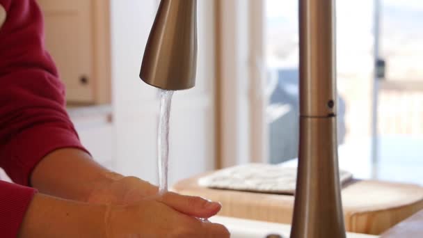 Жінка миє руки біля мийки на кухні — стокове відео