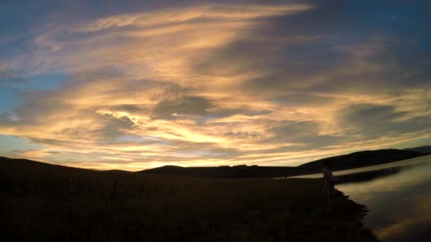 Tonåring fiske vid sjön vid solnedgången i bergen — Stockvideo