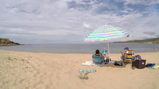 Familia sentada en una playa oceánica juntos — Vídeos de Stock