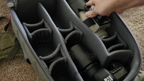 Homem coloca engrenagem da câmera em pacote — Vídeo de Stock