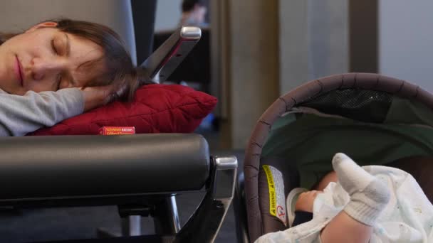 Havaalanında sandalyelere bebekle uyuyan anne — Stok video