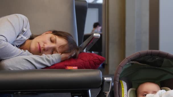 Mother sleeping on chairs in the airport with baby — Stock Video