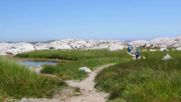 Turister går runt den granitklippor som omger Peggy's Cove lighthouse — Stockvideo