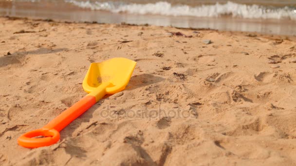 Pala de juguete sentada en la playa del océano — Vídeo de stock