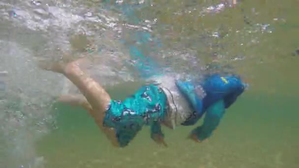 Leuke jongen zwemt aan zandstrand — Stockvideo
