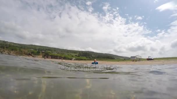 Mały chłopiec pływa na piaszczystej plaży — Wideo stockowe