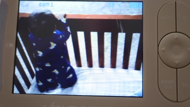 Дивитися, як дитина грає у своєму ліжечку на моніторі — стокове відео
