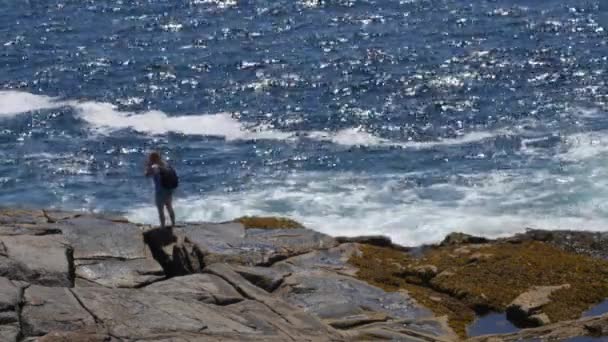 En kvinna som står på den steniga granit kusten — Stockvideo