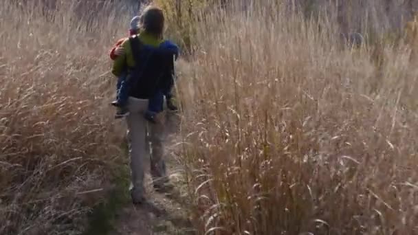 Woman carrying boys hiking on the trail — Stock Video
