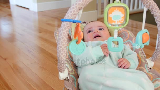 Ein Baby sitzt in einer Wippe — Stockvideo