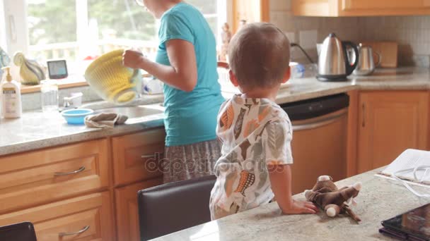 Мальчик облизывает тесто для торта на кухне. — стоковое видео