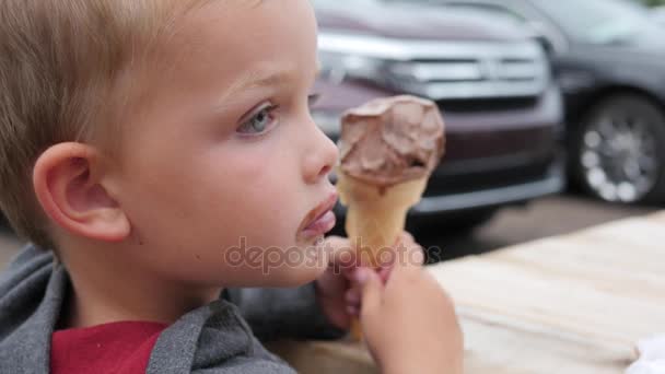 Мальчик ест мороженое в конусе — стоковое видео