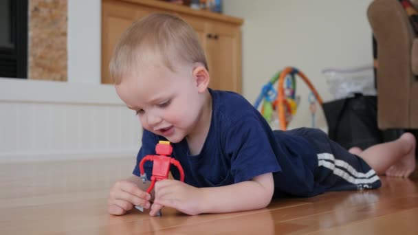 Um menino brincando com robô de brinquedo no chão — Vídeo de Stock