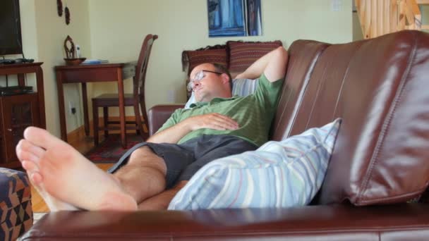 Hombre tomando una siesta en un sofá — Vídeo de stock