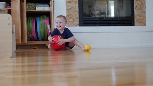 Ein Vater rollt seinem Sohn einen Ball zu — Stockvideo